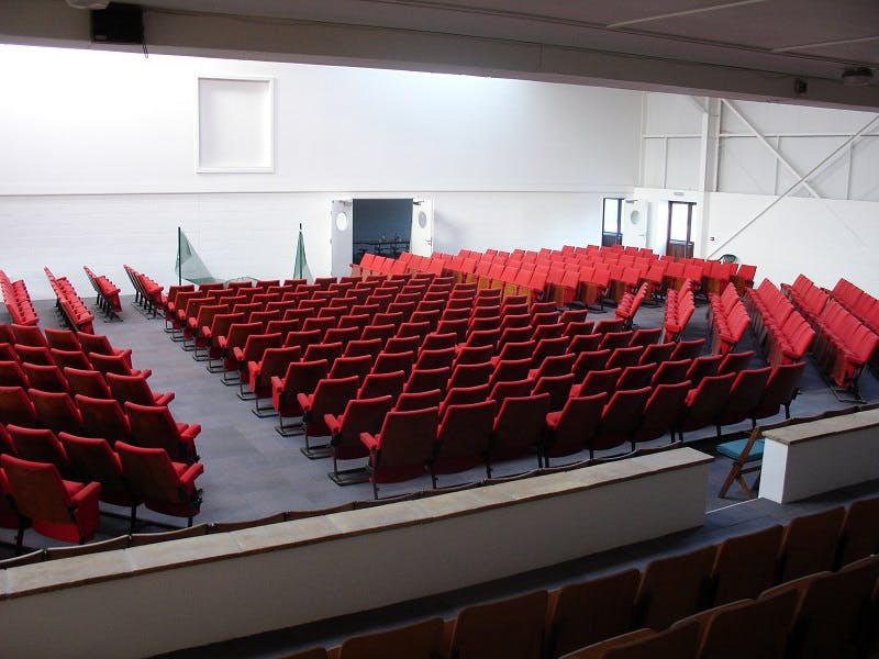 Spacious conference hall with red chairs, ideal for events and presentations.