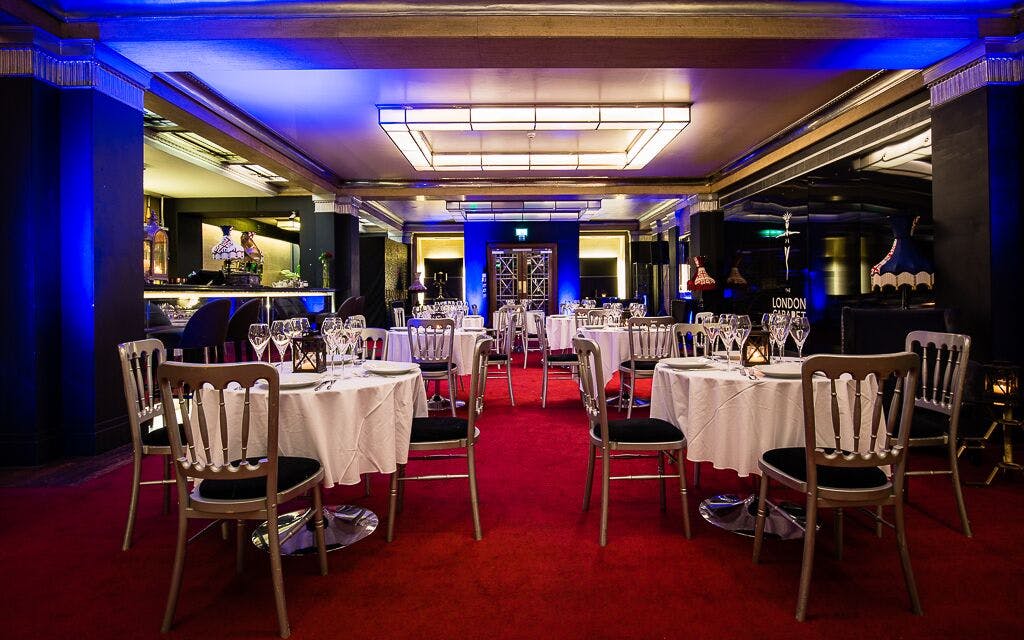 Elegant dinner setup at The Rose Bar, featuring white linens and blue ambient lighting.