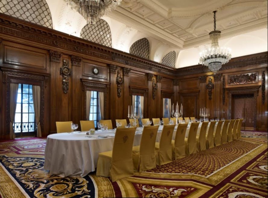 Elegant ballroom with long dining table, ideal for exclusive meetings and events.
