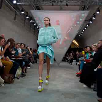 Model on runway at The Big Black One fashion event with triangular projection.