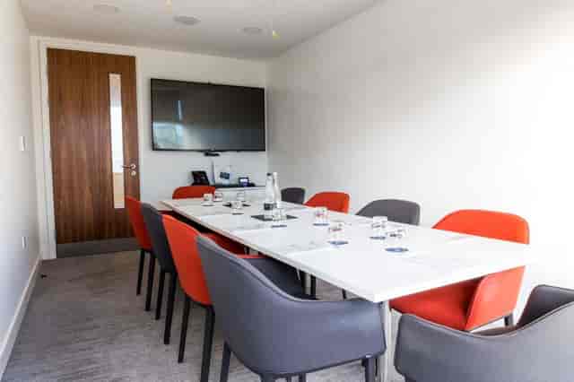 Modern meeting room at The Royal Pharmaceutical Society with sleek table and vibrant chairs.