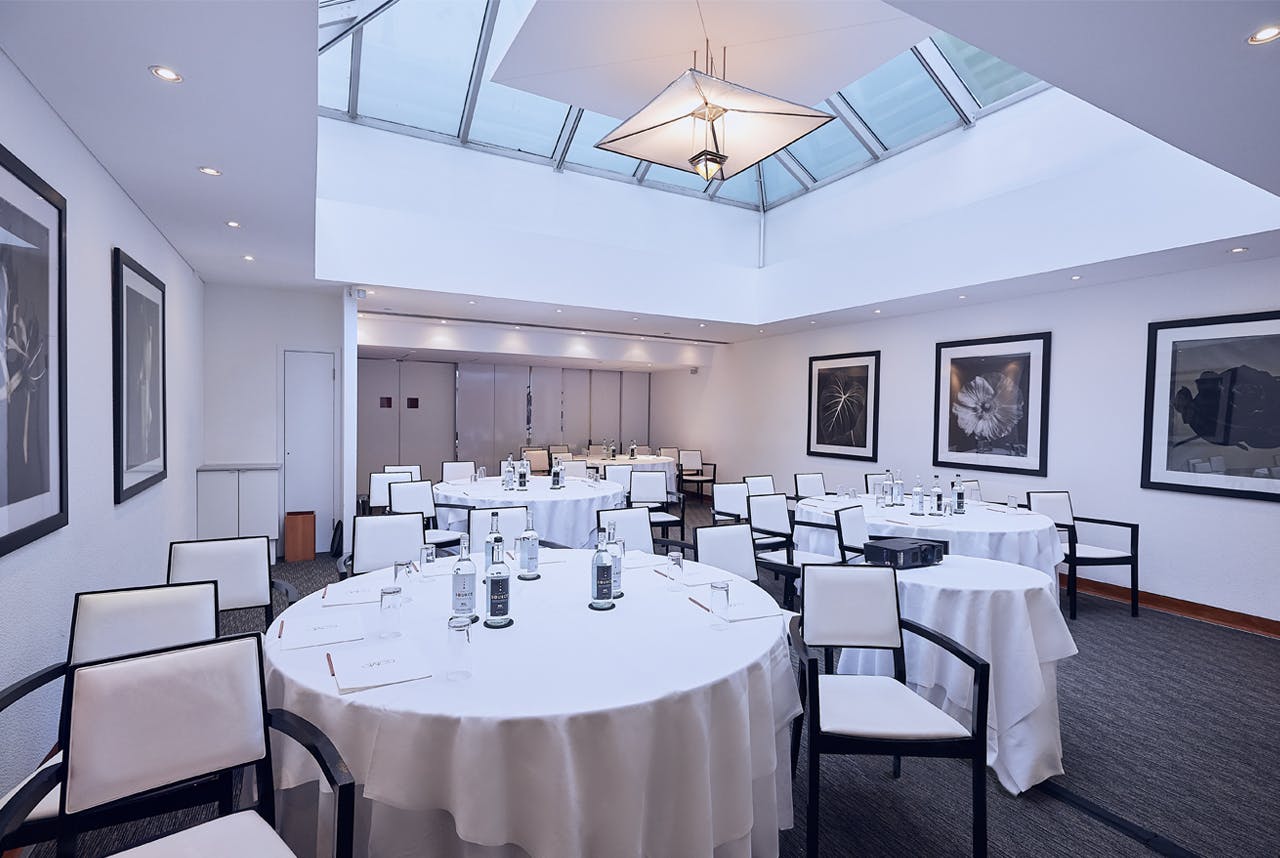 White Room at COMO Metropolitan London, elegant meeting space with round tables and skylight.