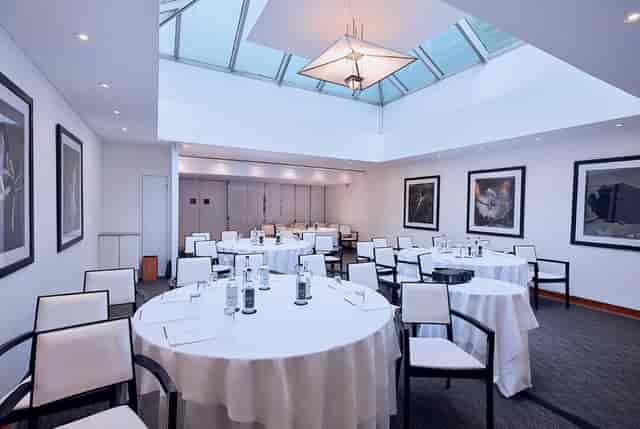 White Room at COMO Metropolitan London, elegant meeting space with round tables and skylight.