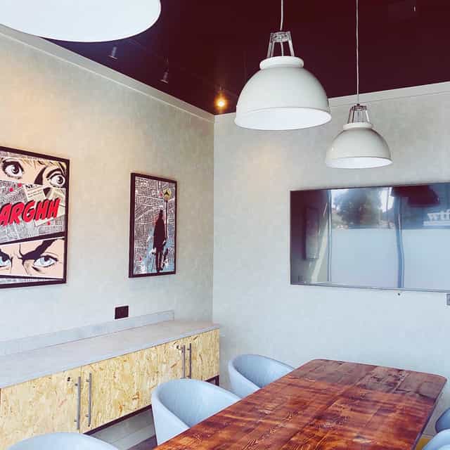 Modern meeting space at Holiday Inn Whitechapel with wooden table and vibrant artwork.