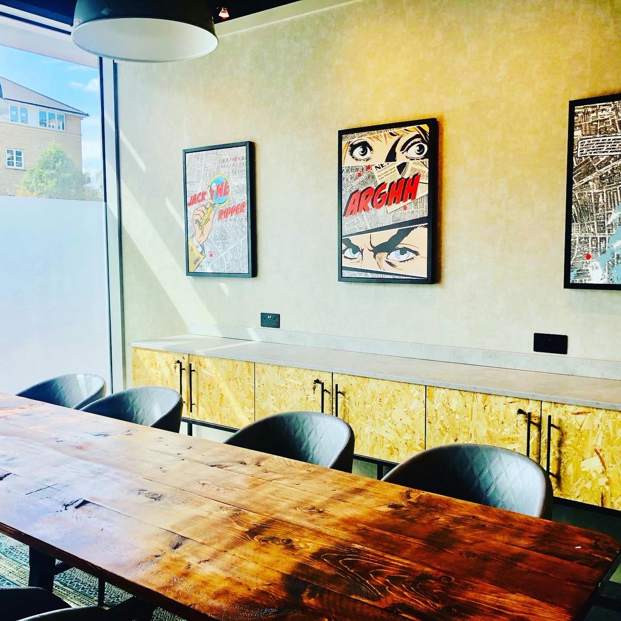 Modern meeting room at Holiday Inn Whitechapel with wooden table and vibrant artwork.