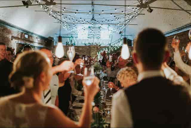 Wedding reception in Shoreditch Studios with guests toasting under string lights.