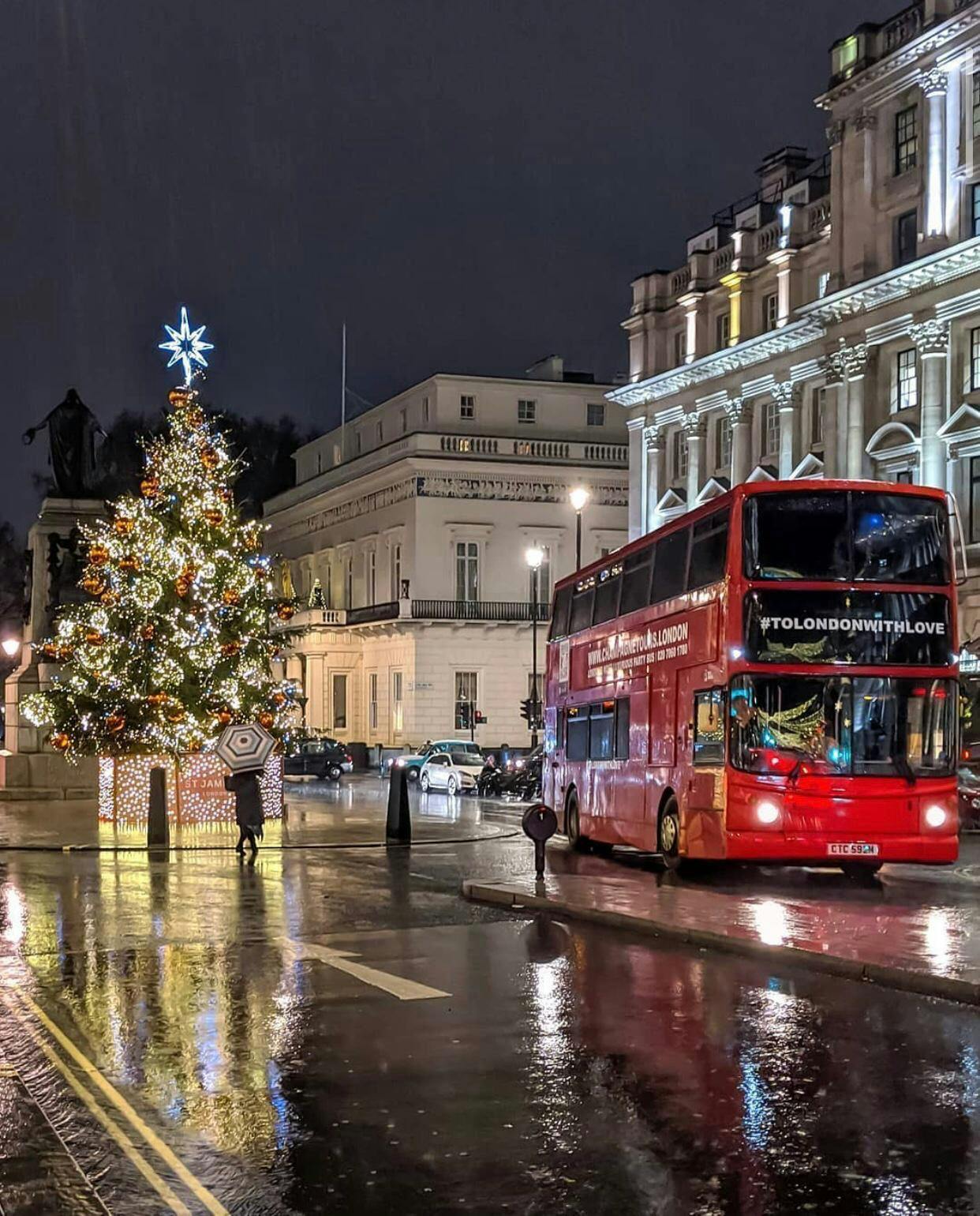 Luxury double-decker bus by Christmas tree in London, perfect for holiday tours.