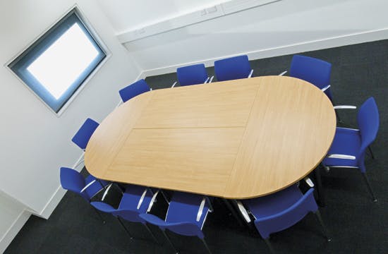 Meeting room with oval wooden table and blue chairs, perfect for brainstorming sessions.