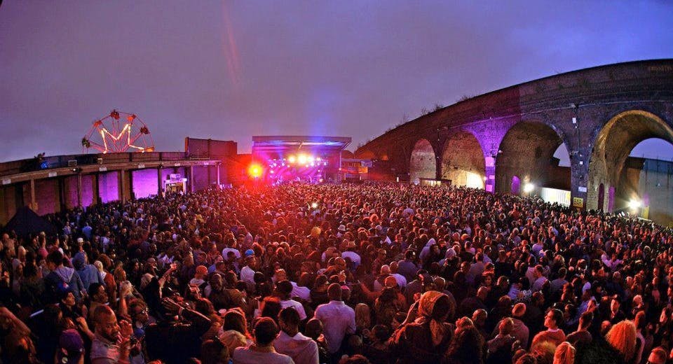 Vibrant outdoor concert at The Rainbow Venues with colorful stage lights and large crowd.