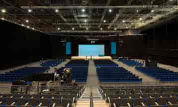 Spacious ACC Liverpool venue with blue chairs set for a large conference presentation.