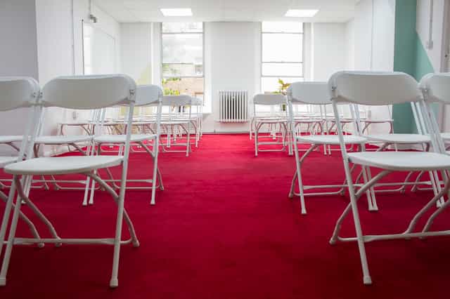 Events Space in Space4 with white chairs on red carpet, perfect for workshops and seminars.