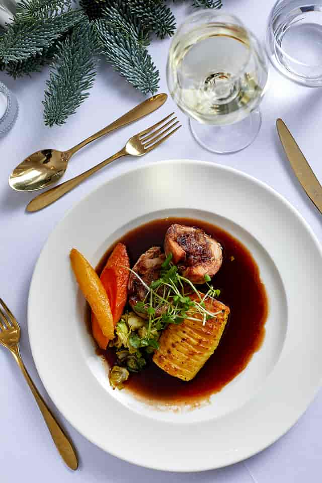 Elegant plated dish with roasted vegetables for upscale Christmas events.