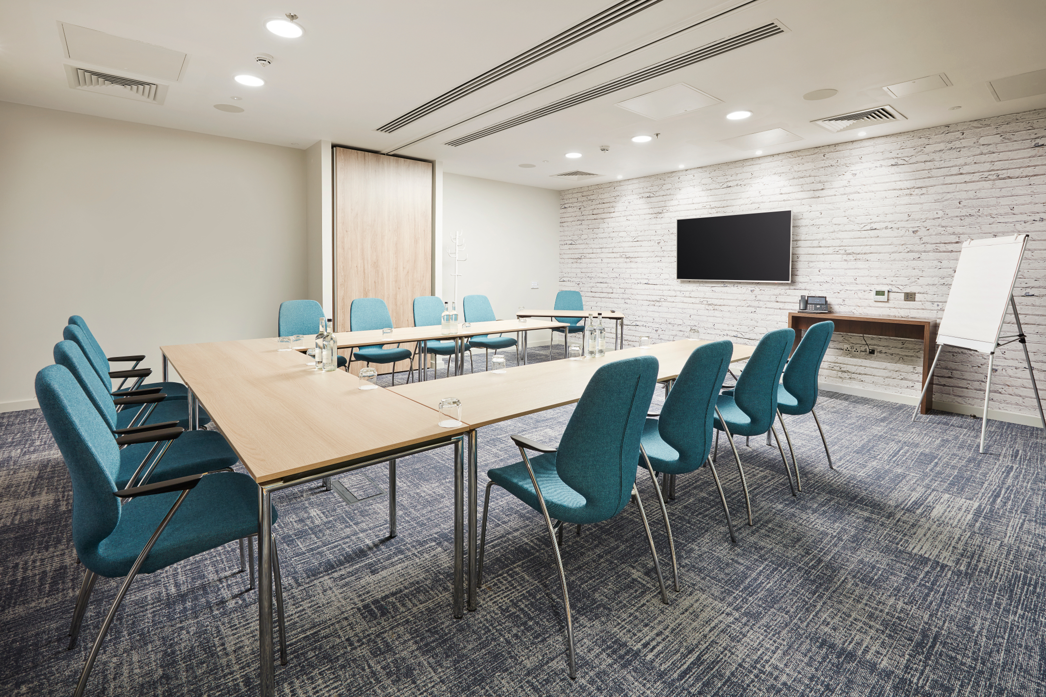Modern meeting room with light wood tables, ideal for workshops and team discussions.