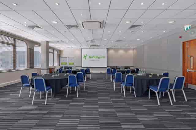Dylan in a bright Holiday Inn meeting room with round tables for events and workshops.