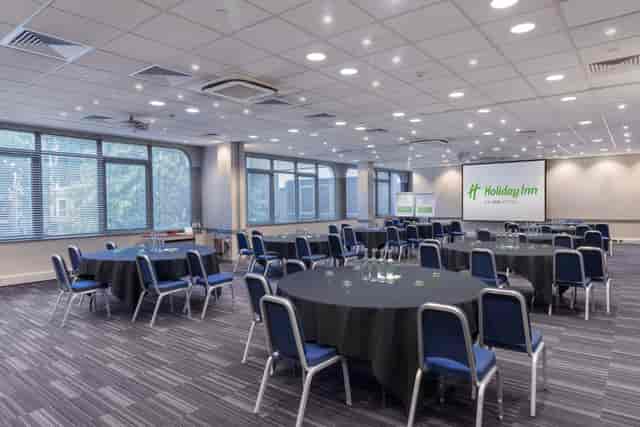 Meeting room at Holiday Inn London with round tables, ideal for events and presentations.