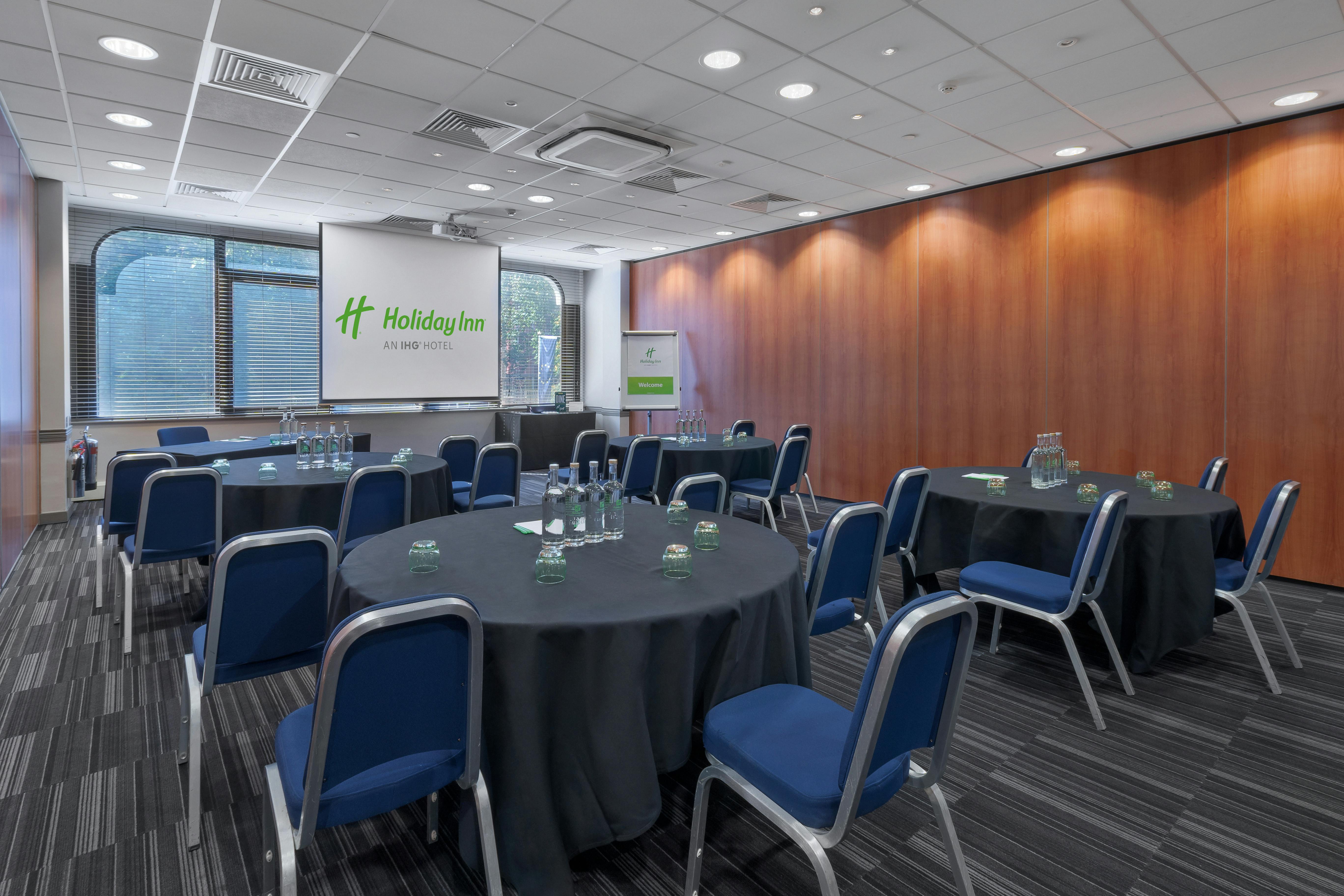 Corporate meeting space with round tables at Holiday Inn London Kensington Forum.