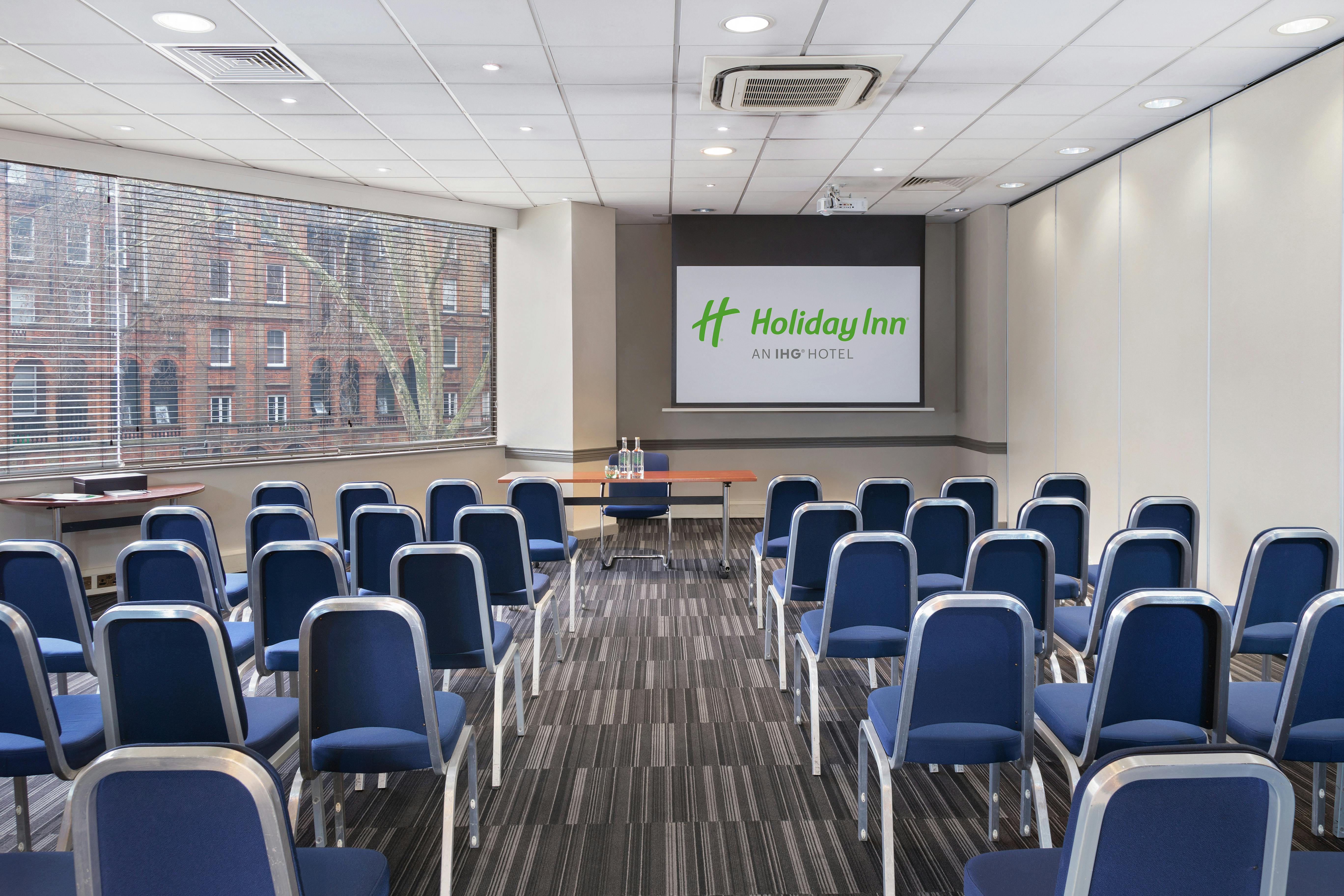 Madonna in a modern meeting room with blue chairs for corporate events at Holiday Inn.