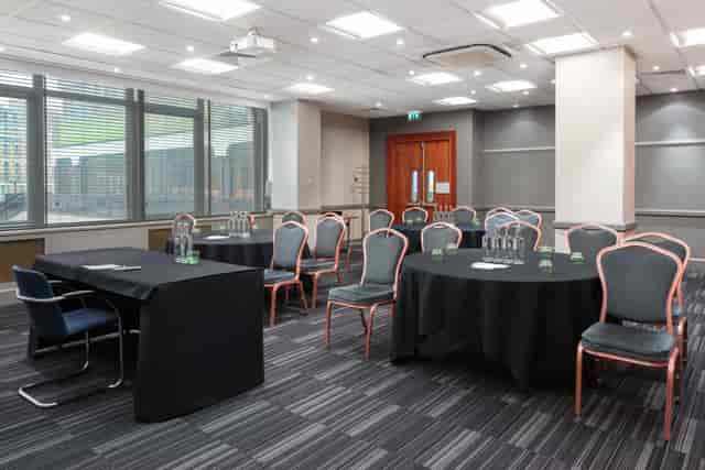 Hockney in a meeting room with round tables, ideal for events and presentations.