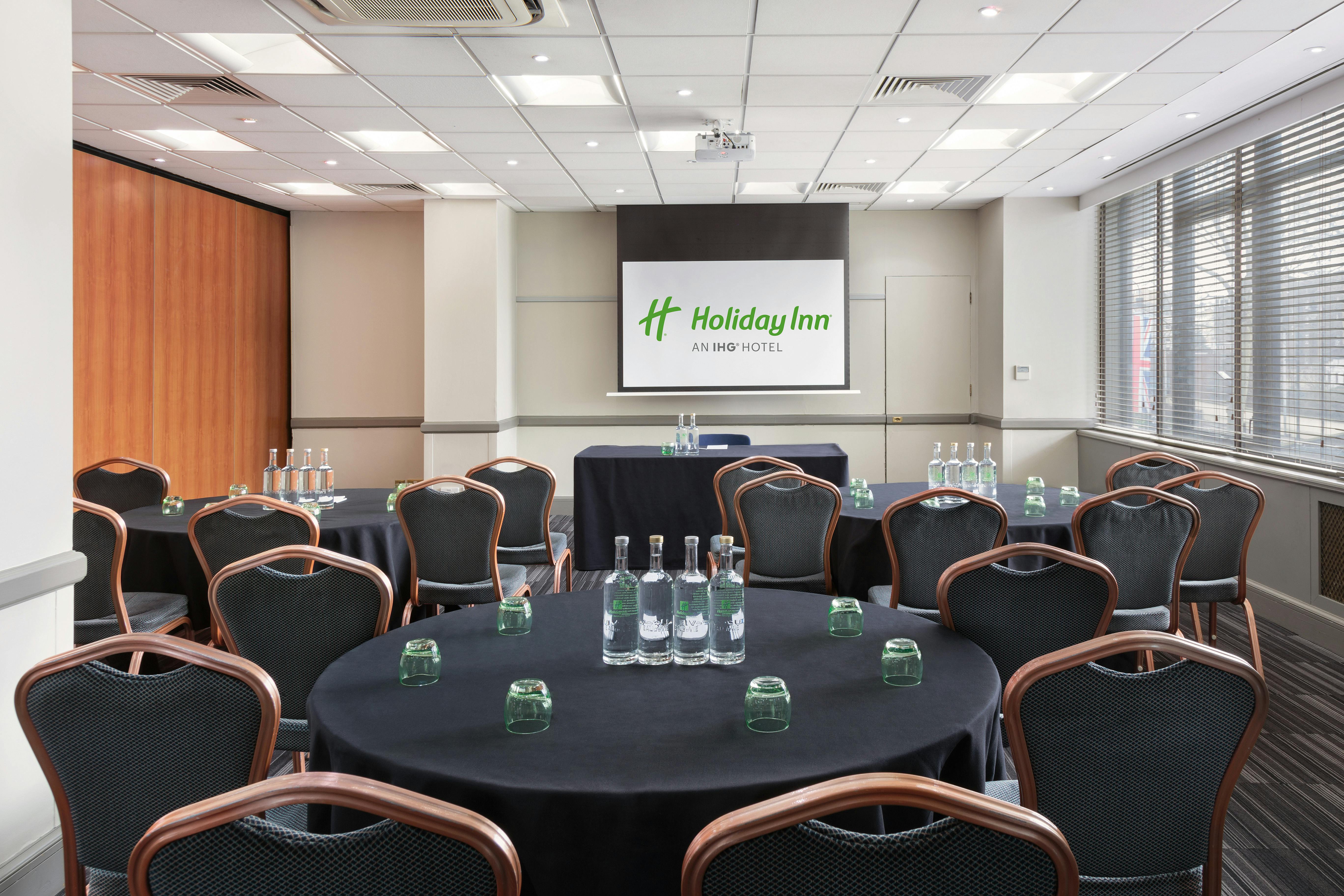 Meeting room at Holiday Inn London with round tables, ideal for corporate events.