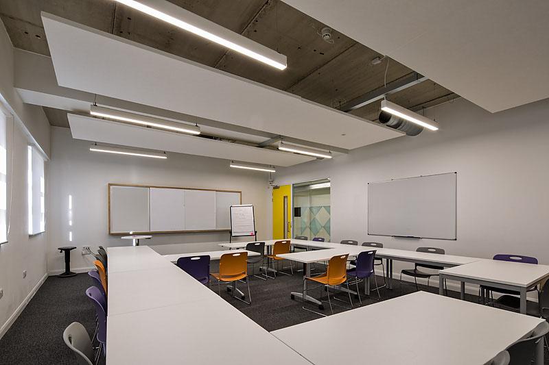 Ground floor classroom with modular tables for workshops at Ada National College. - Banner
