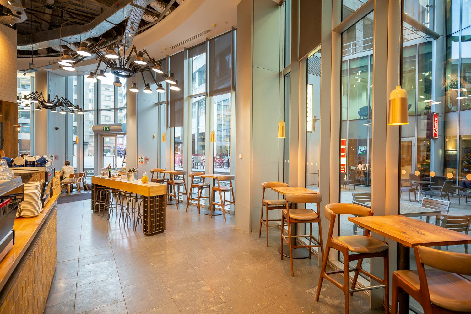 Modern café space with large windows, perfect for networking events and informal meetings.