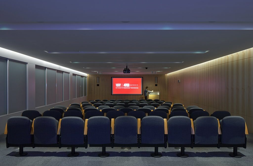 Auditorium conference room with tiered seating, ideal for meetings and presentations. - Banner