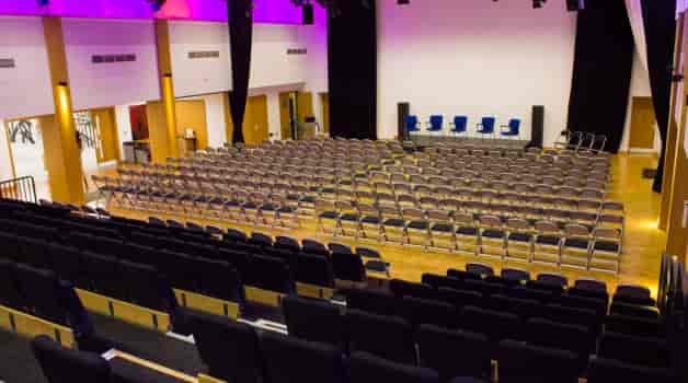 Queen's Park Community School auditorium stage, theater-style seating for events and conferences.