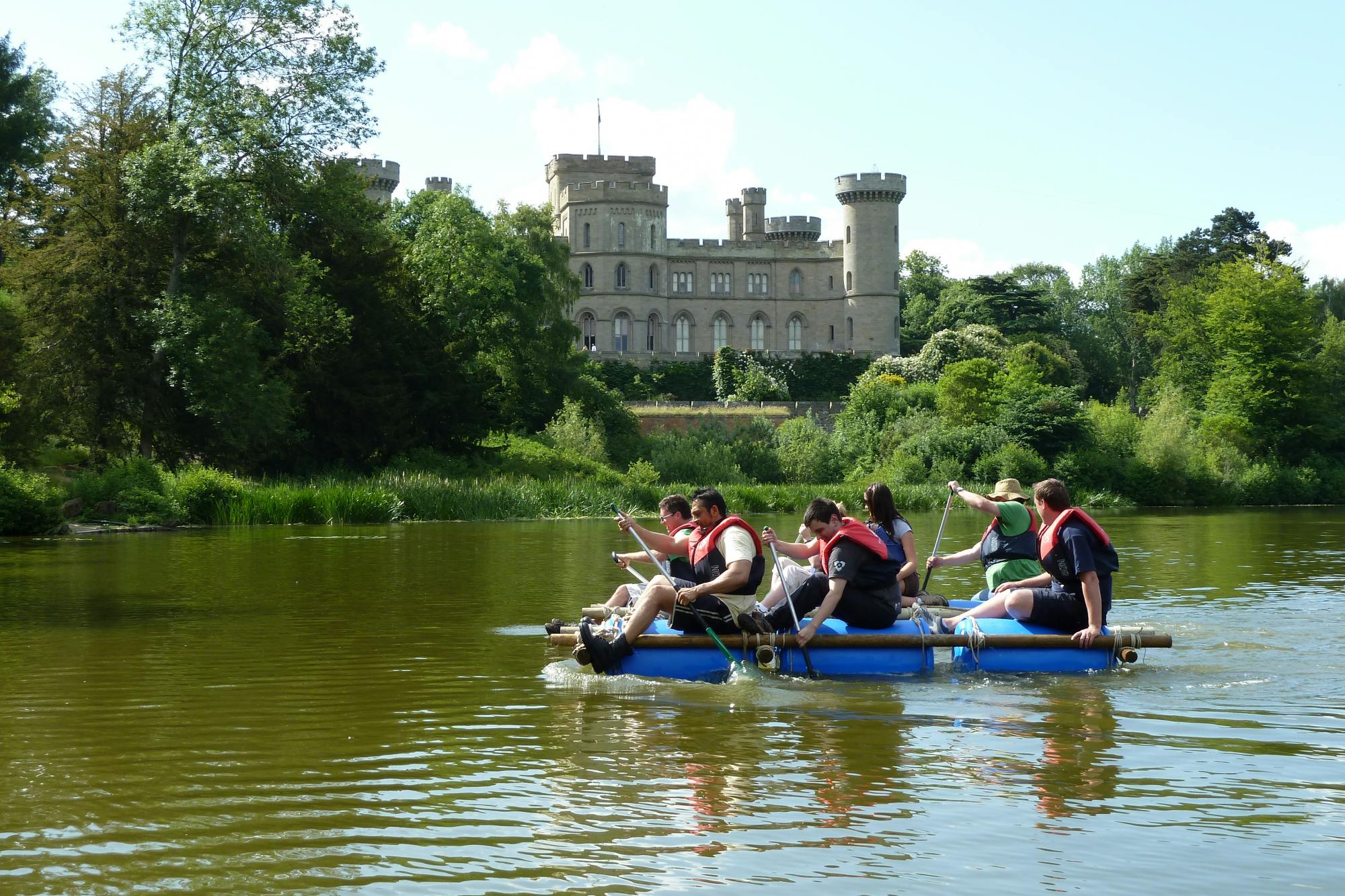 Team-building activity on serene lake at Eastnor Castle with makeshift raft.