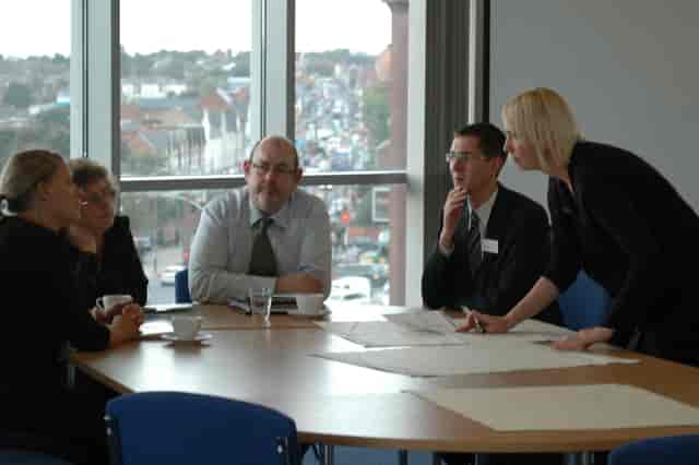 Corporate strategy breakout session in Nishkam Centre boardroom with natural light.
