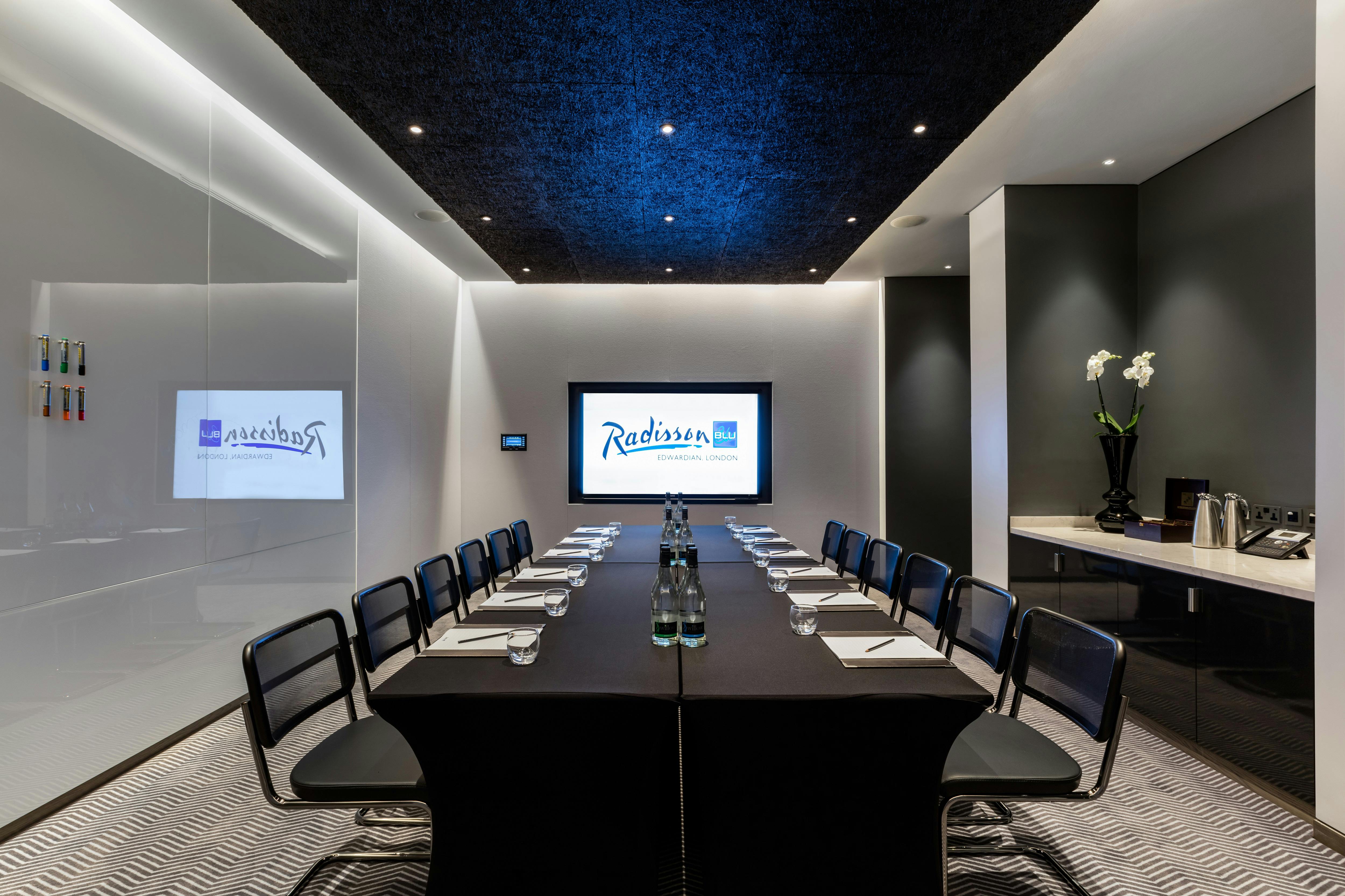 Modern meeting room at Radisson Blu London with sleek table and large screen.