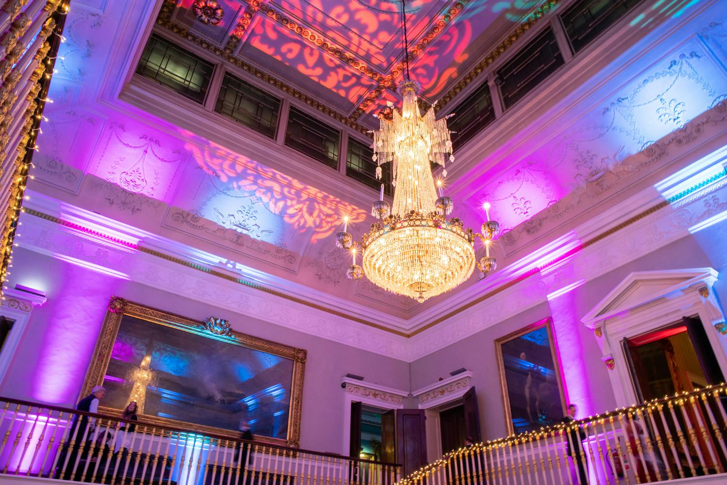 Elegant event space at Waterloo, featuring chandelier and vibrant uplighting for upscale gatherings.