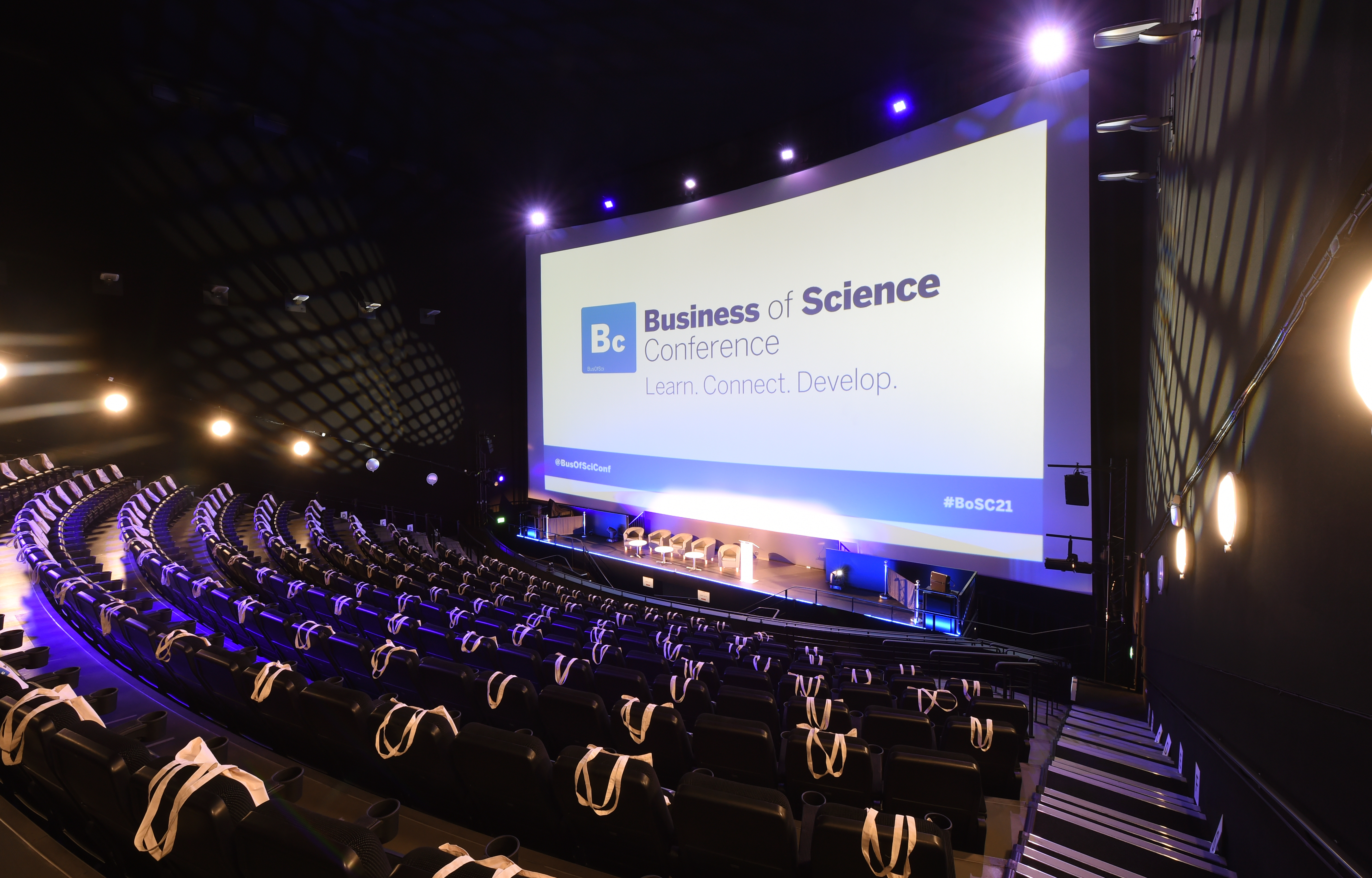 Modern auditorium with tiered seating for Business of Science Conference networking event. - Banner