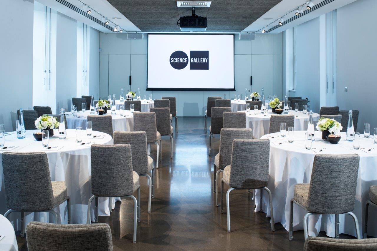 Modern event space with round tables and floral centerpieces for conferences in London. - Banner