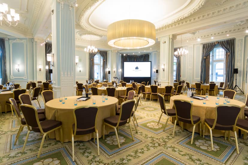 Elegant conference space at The Trafford, featuring gold-draped tables and presentation screen.