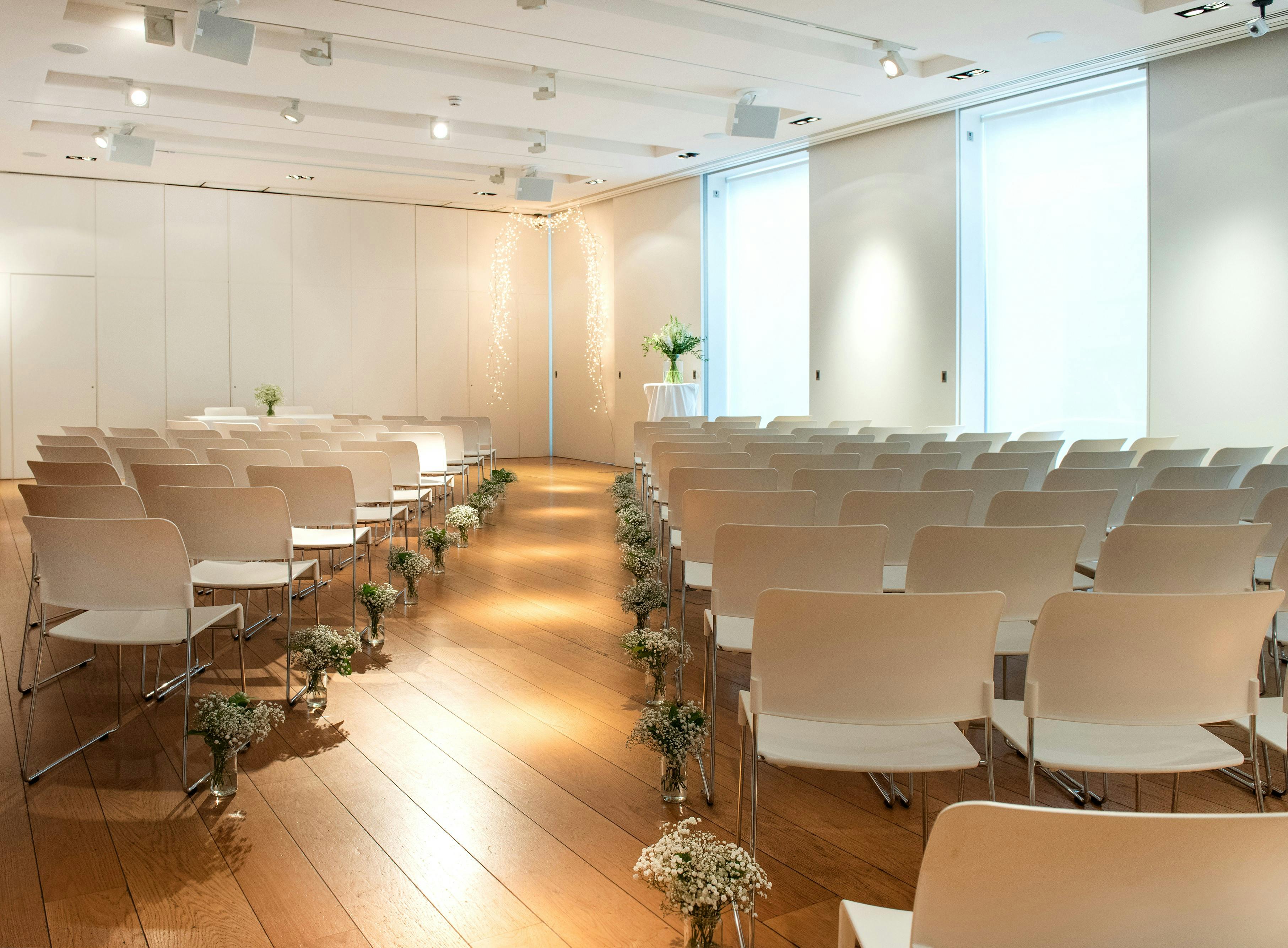 Exhibition Room at The Goldsmiths' Centre with white chairs for elegant ceremonies and presentations.