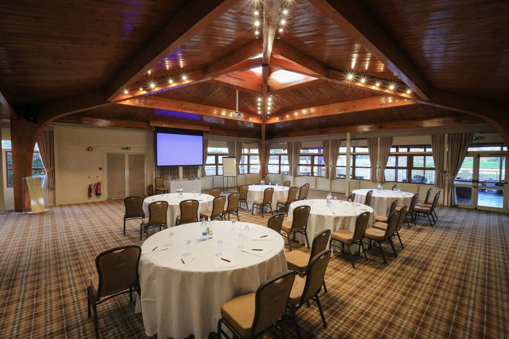 Event space at Woburn Safari Lodge with round tables, ideal for corporate meetings.