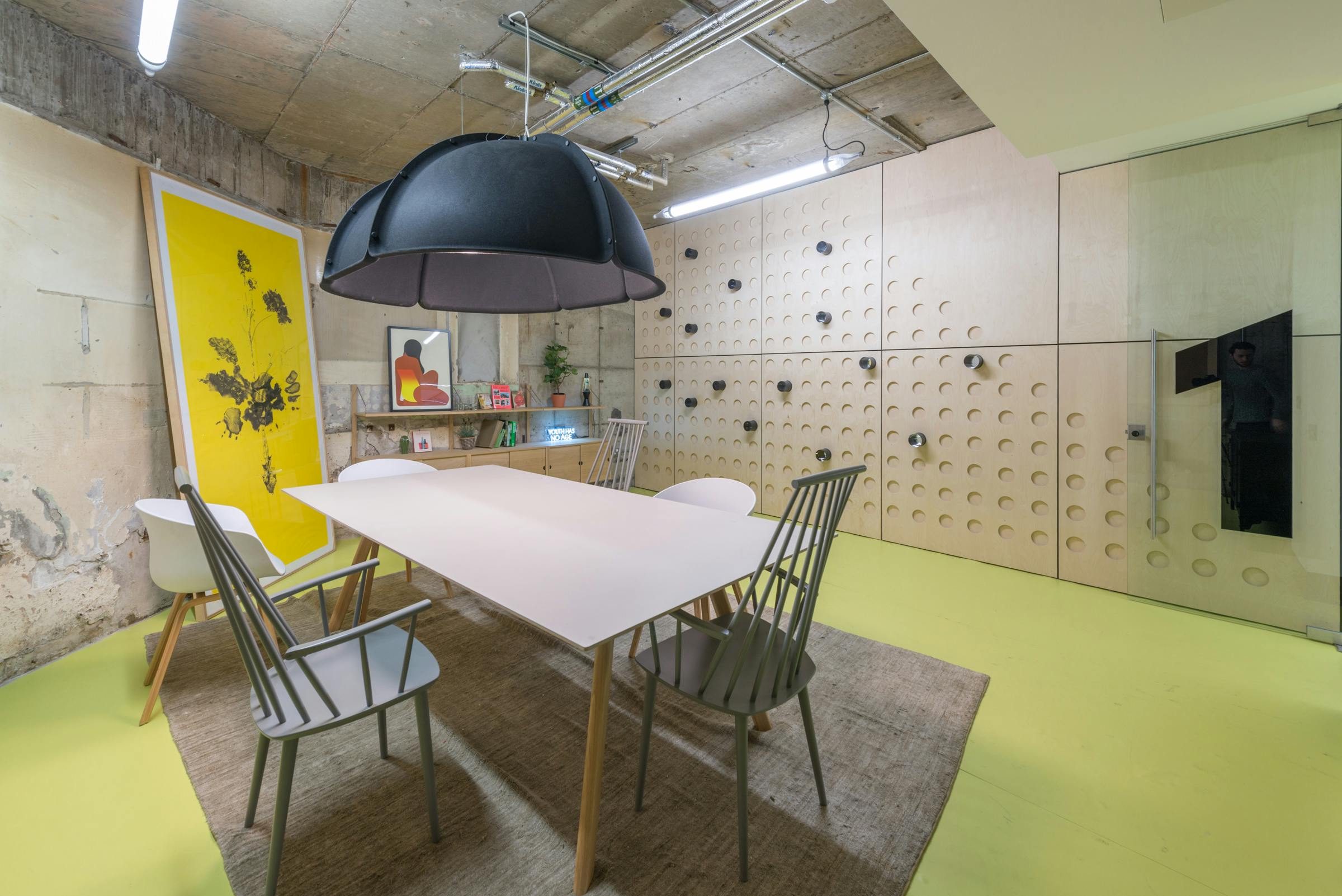 Modern meeting room with large table, vibrant yellow accents for workshops and brainstorming.