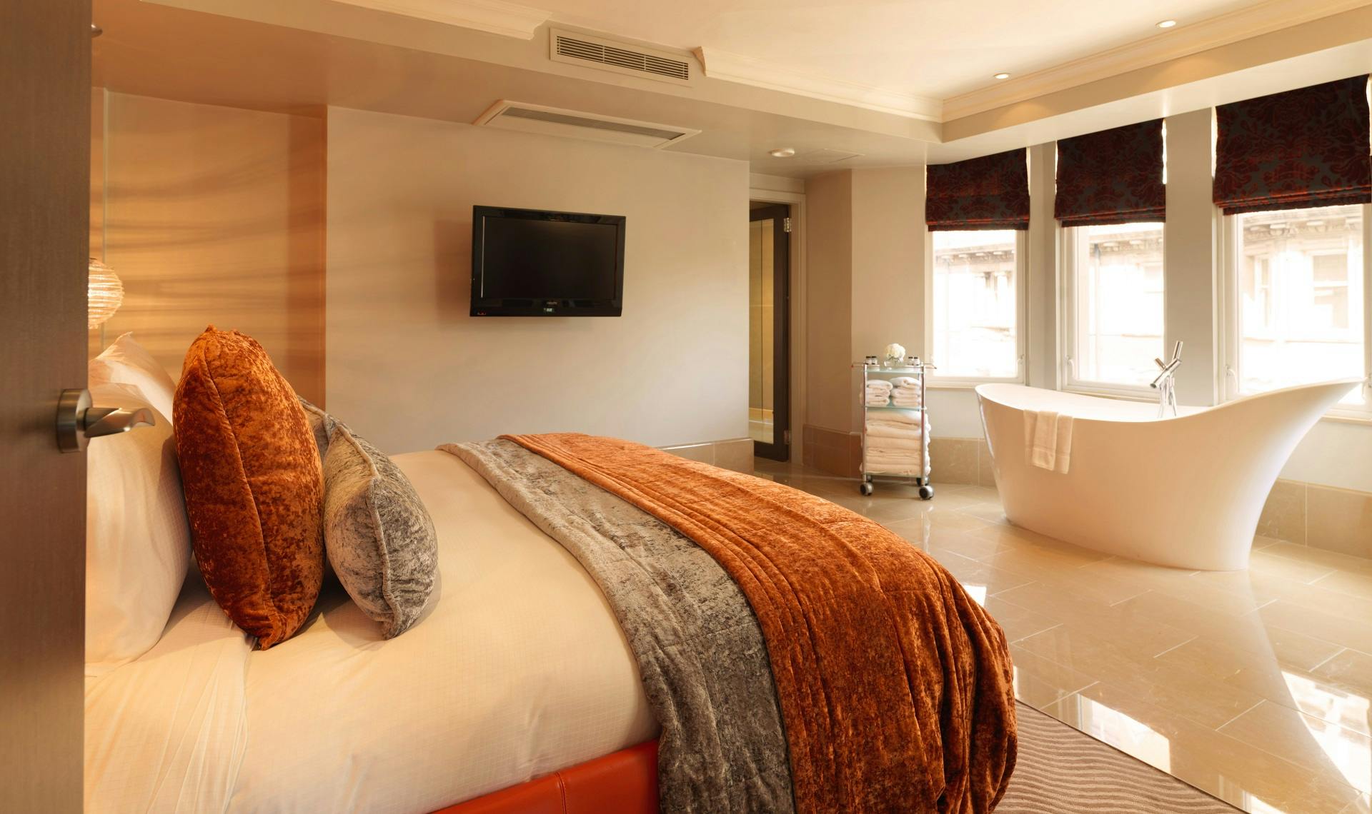 Luxurious hotel room at Radisson Blu London, featuring plush bed and stylish bathtub.