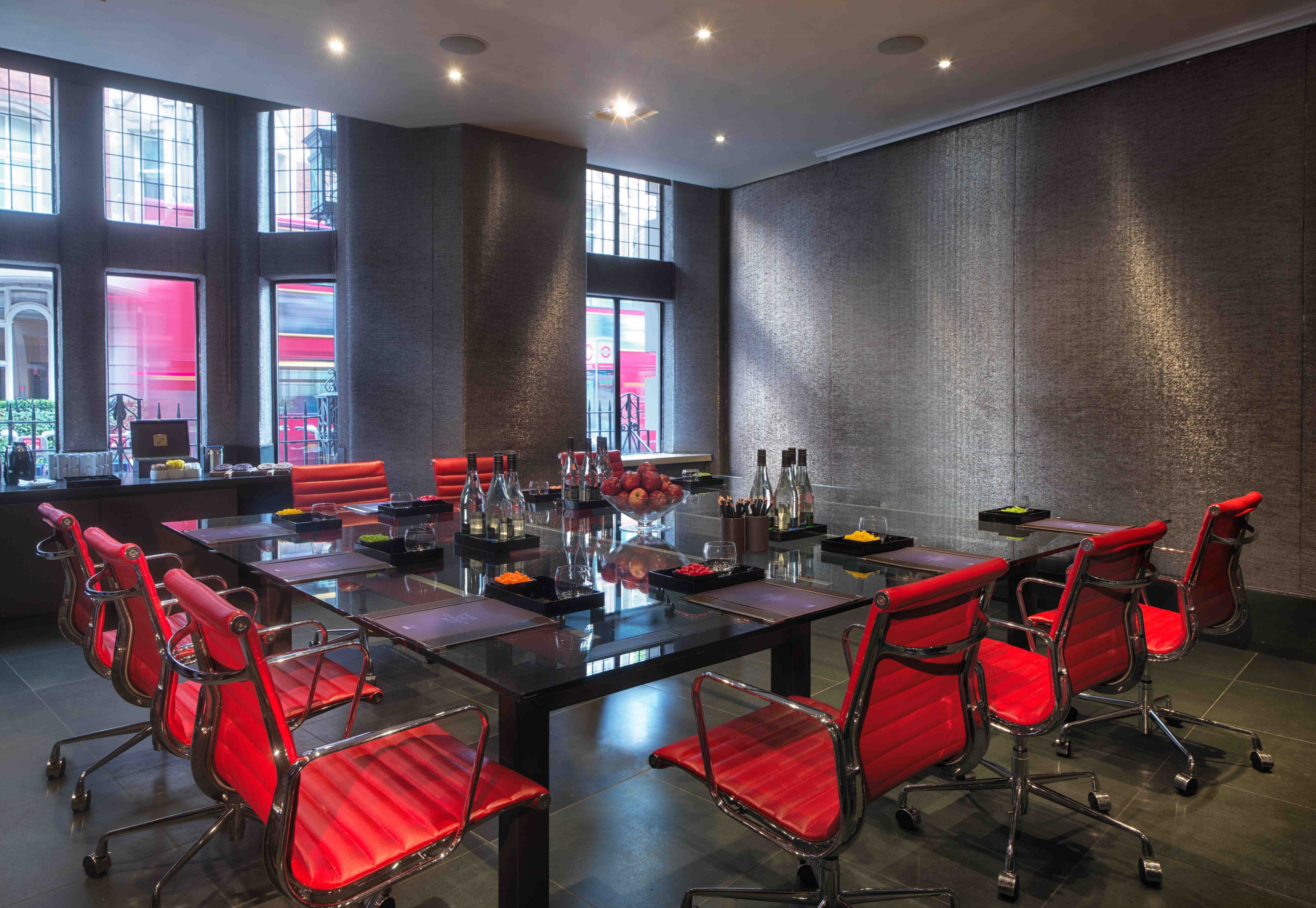 Modern meeting room with glass table and red chairs at Radisson Blu Hotel, London.