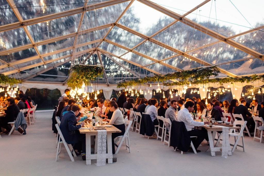 Elegant dining setup in a clear-top tent for networking and celebrations at Greenhaus.