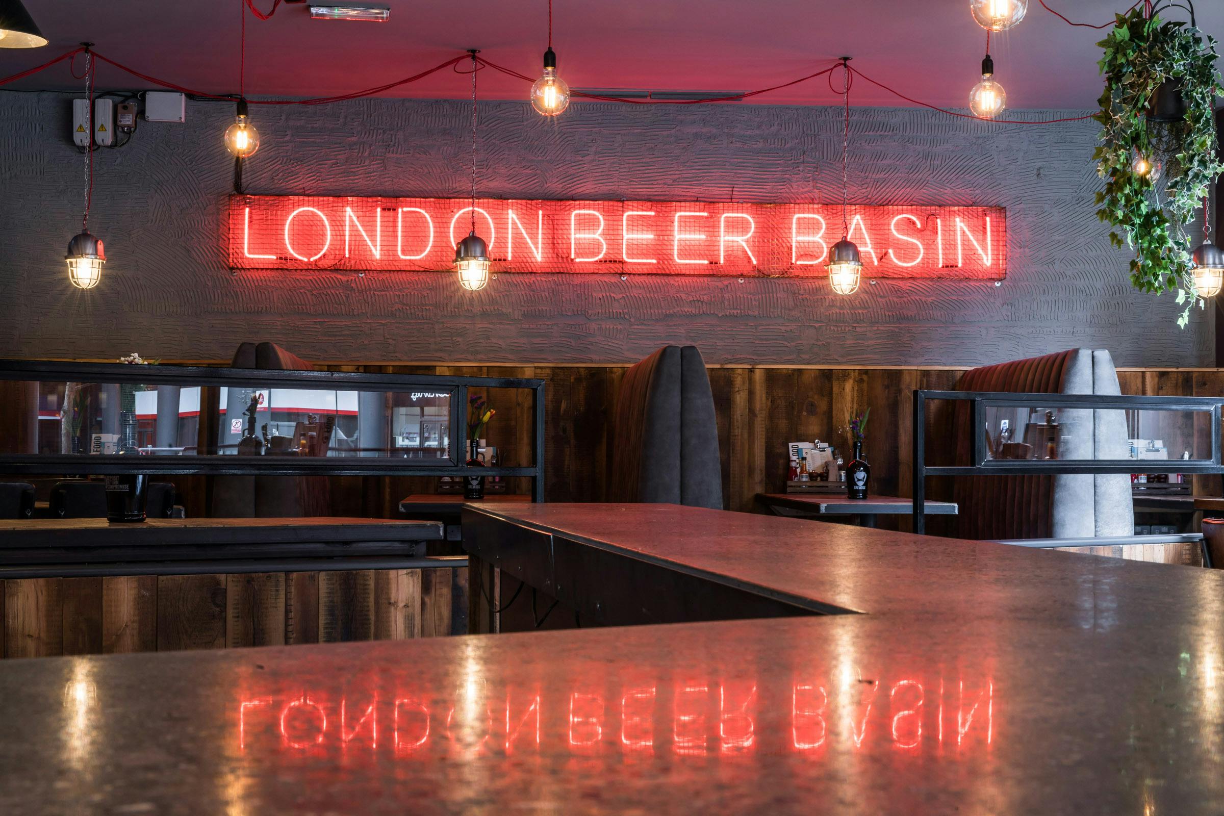 Vibrant BrewDog Paddington venue with neon "LONDON BEER BASIN" sign for events.