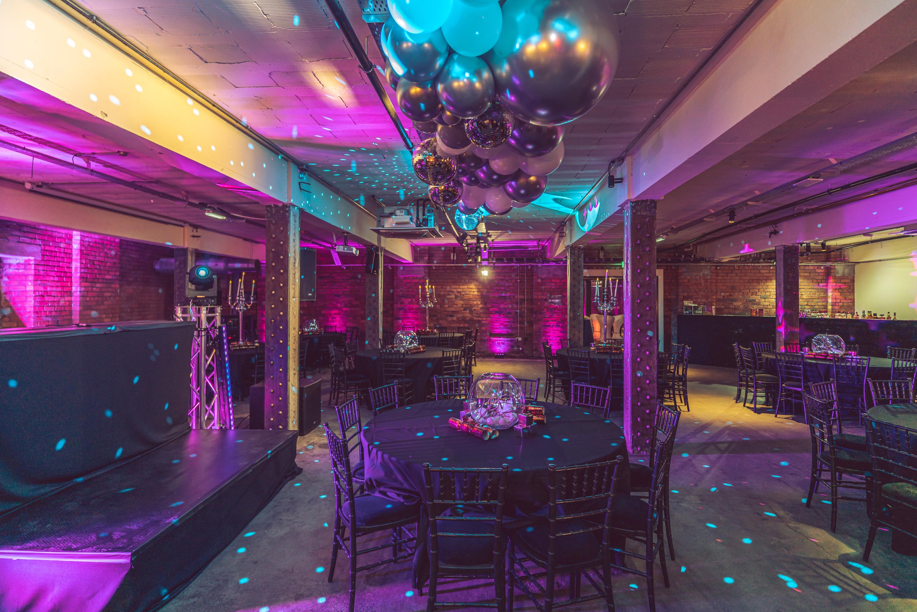 Elegant event space at The Cellars, Victoria Warehouse, with vibrant lighting and round tables. - Banner