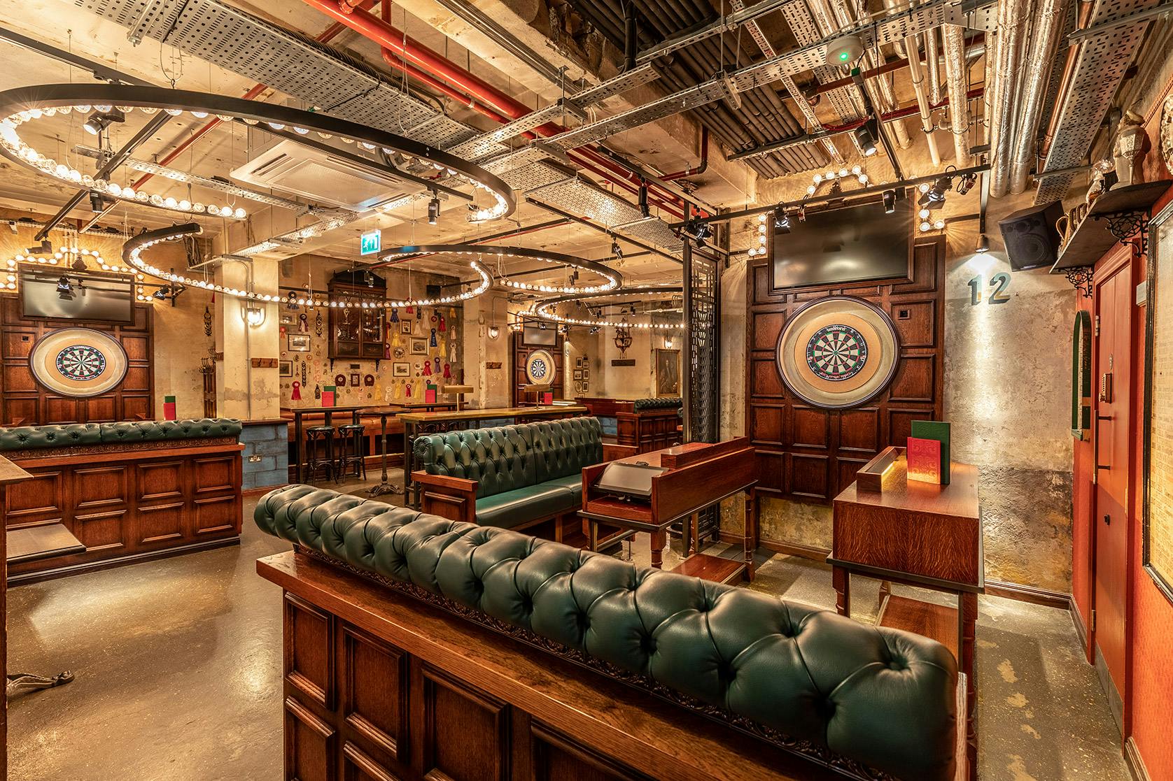 Stylish event space with green leather seating at Flight Club Shoreditch for gatherings.