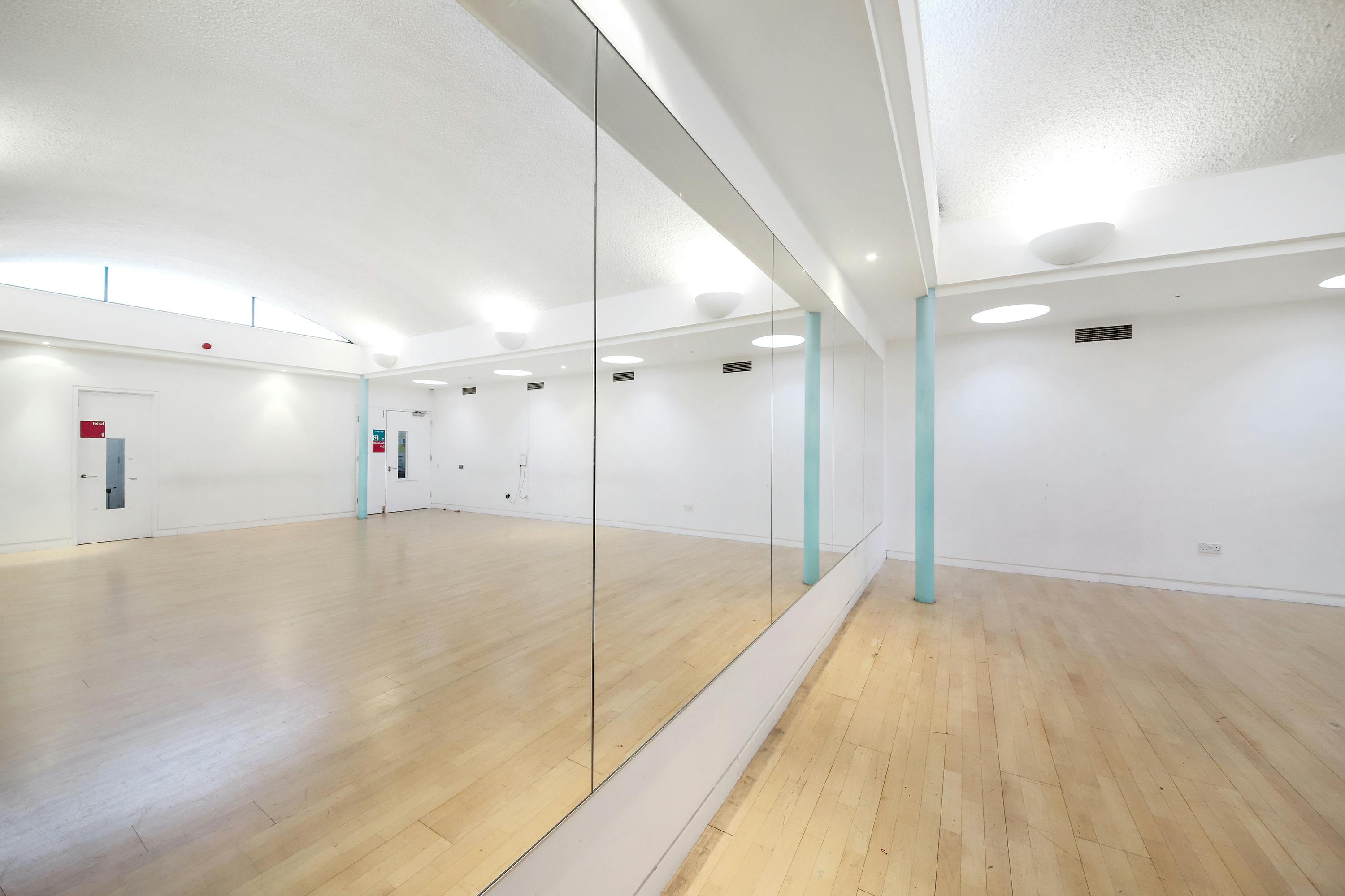Spacious event space with polished wooden floors for workshops and fitness classes.