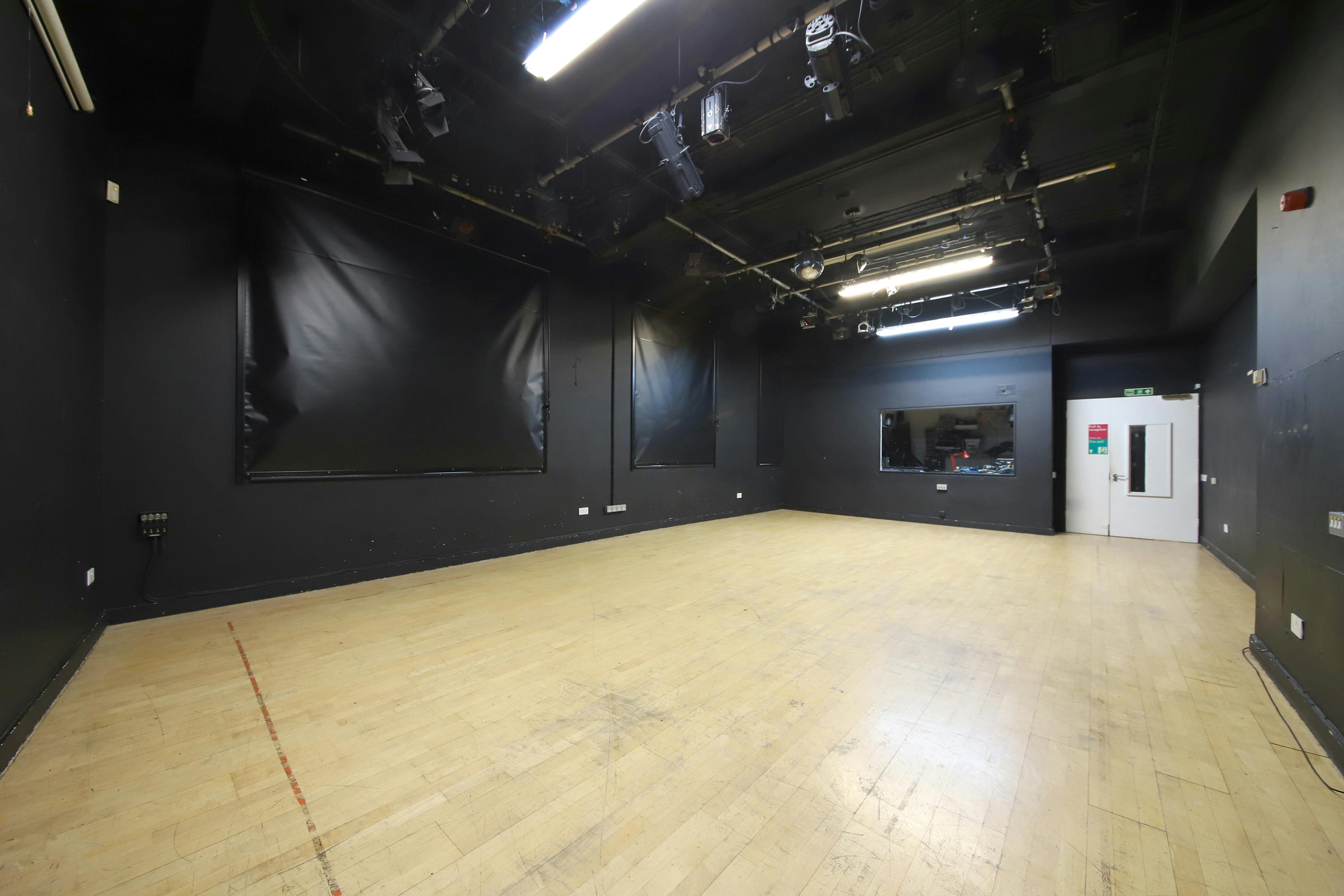 Versatile minimalist event space with dark walls for workshops and presentations.