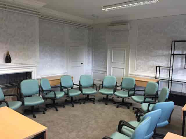 "Teal chairs in a bright meeting space at Barnett Hill Hotel for team discussions."