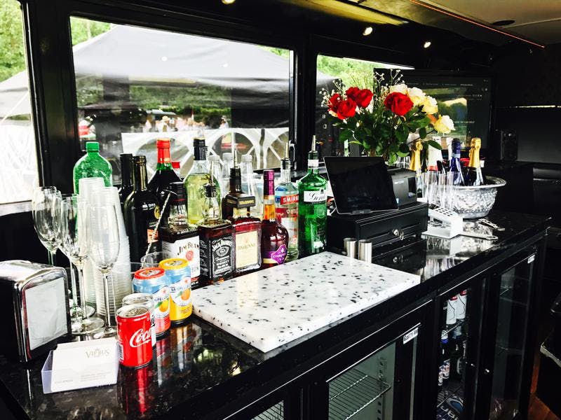 VIP bus bar with sleek black counter, elegant glassware for events and celebrations.