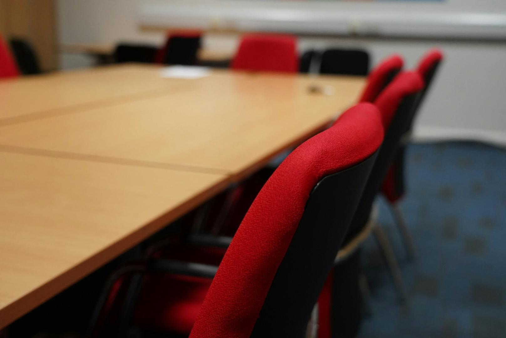 Meeting Room 1 at HAD with a large wooden table and red chairs for collaborative sessions.