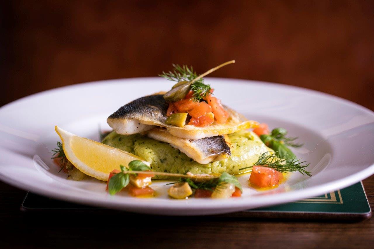 Plated fish dish with herbs and tomatoes at Apple Vault, Covent Garden - upscale dining event.