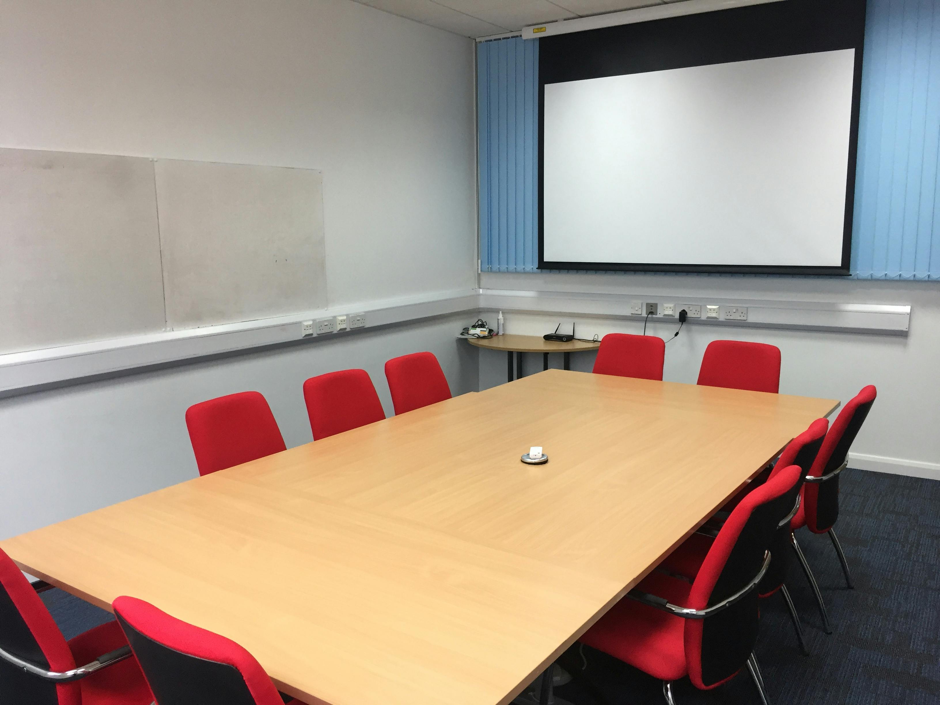 Meeting Room 5 at HAD with wooden table, red chairs for productive meetings and presentations.